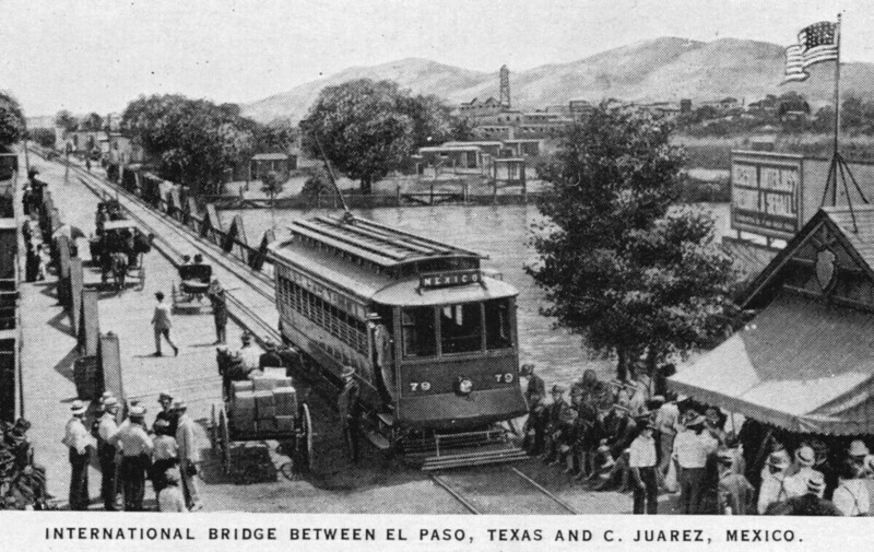 Photograph of carriages and trolley on international bridge at US Customs checkpoint surrounded by people