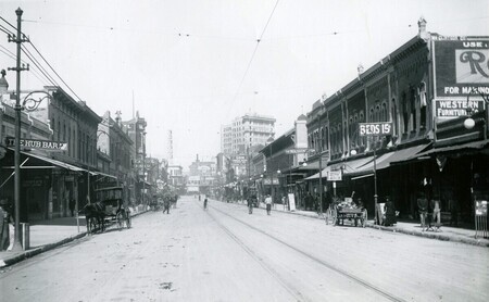 View of downtown El Paso Street with concrete and brick buildings, wagons, bicycles, and streetcar rails